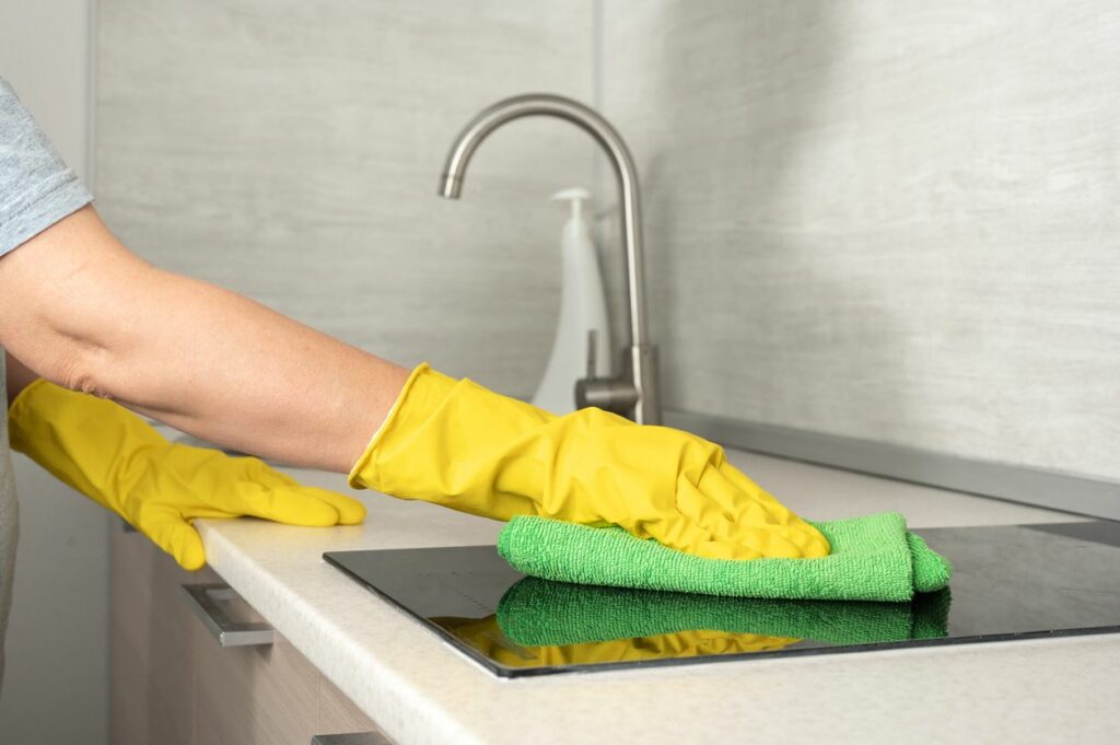 A person wiping down their kitchen counter with a green cloth
