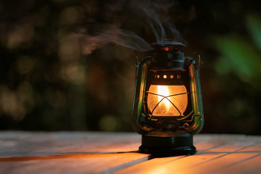 Lantern lit on a wooden table outdoors.